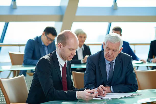 Two businessmen reviewing loan documents and financial paperwork
